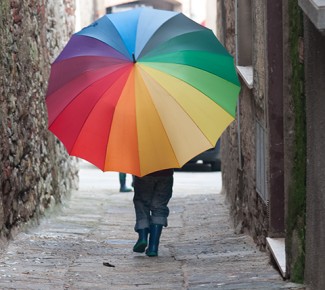 Kind mit großem, bunten Regenschirm